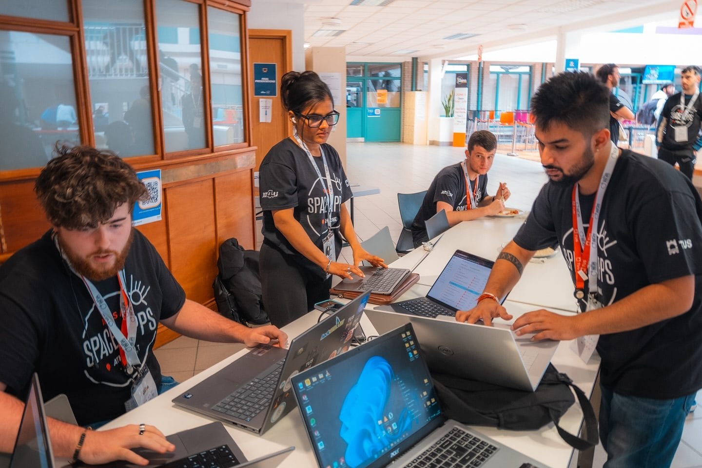 Crew members in NASA Space Apps Athlone T-shirts working on laptops at HackAthlone 2025