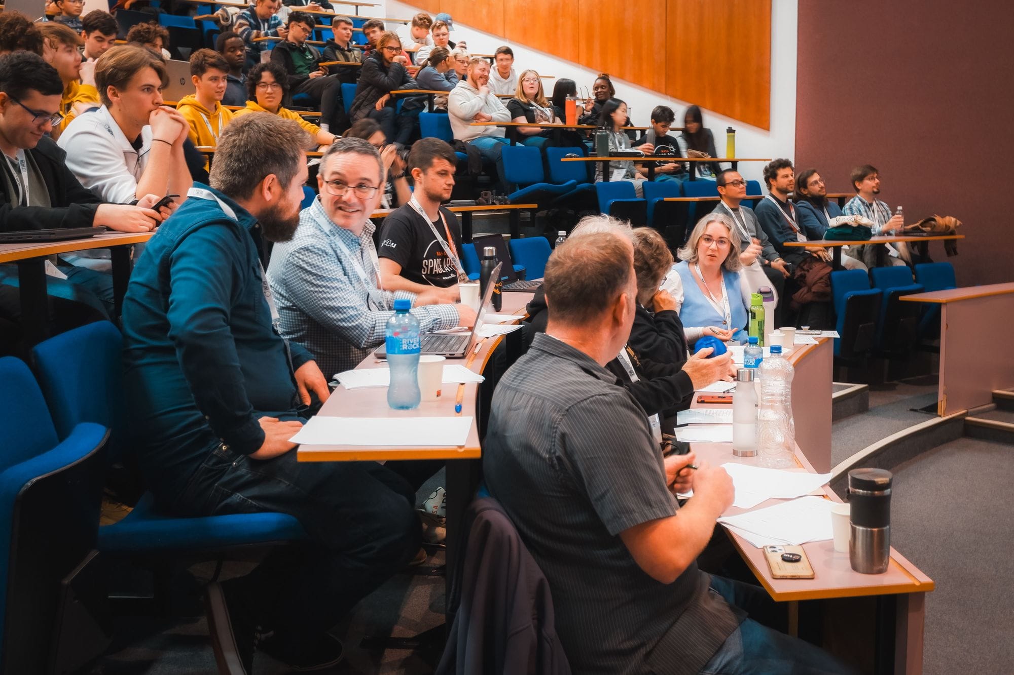 The judges’ desk, with scoring sheets and laptops, at the front of a full lecture theatre during the HackAthlone 2025 final presentations